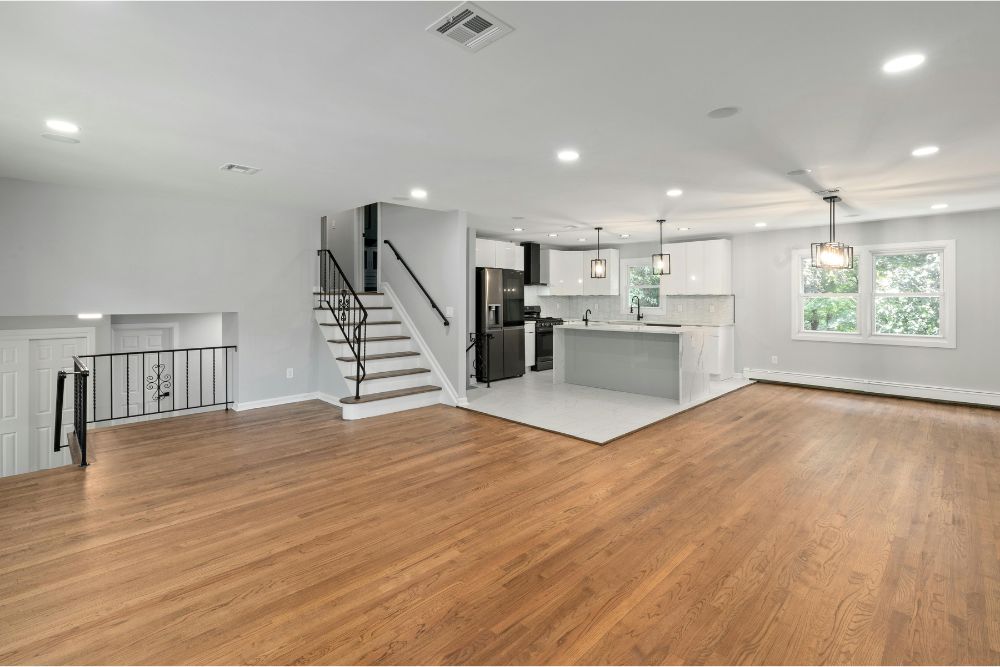 Beautifully remodeled NYC basement with white staircase by Grace General Construction Corp, offering expert basement renovation, finishing, and conversion services.