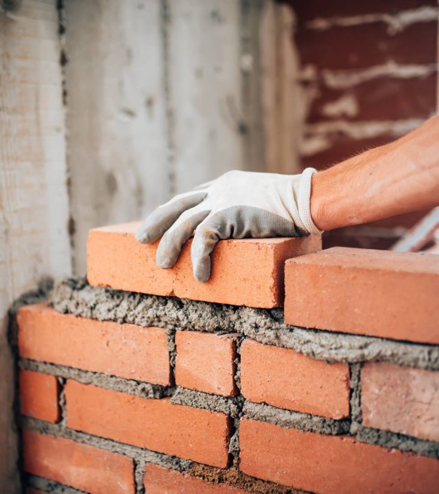 Construction worker laying bricks on exterior walls Construction worker laying bricks on exterior walls